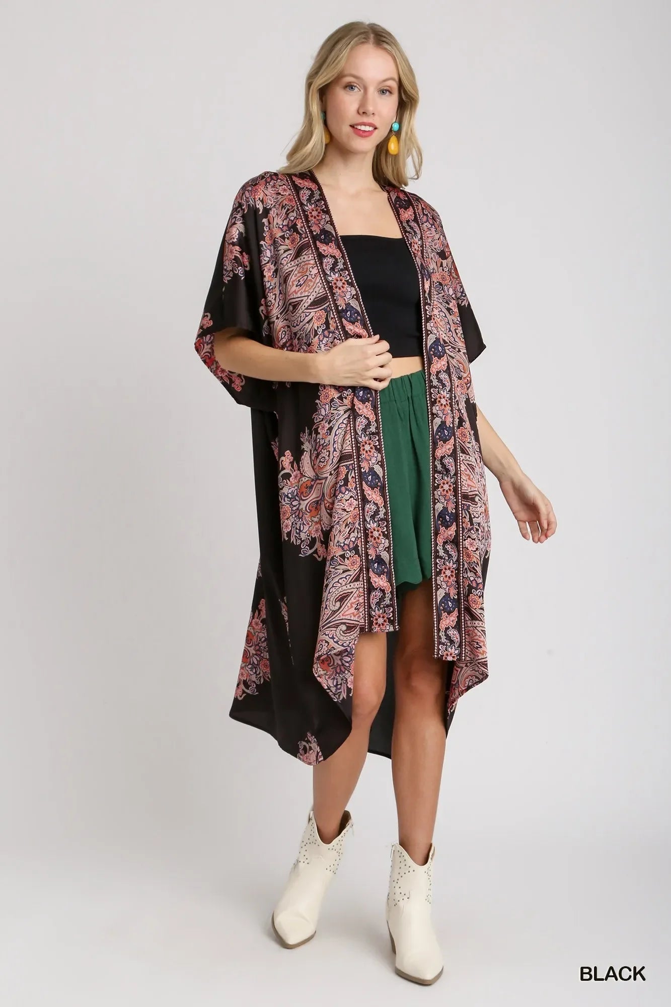 Black floral kimono with paisley print, worn over black top and green shorts, paired with white boots