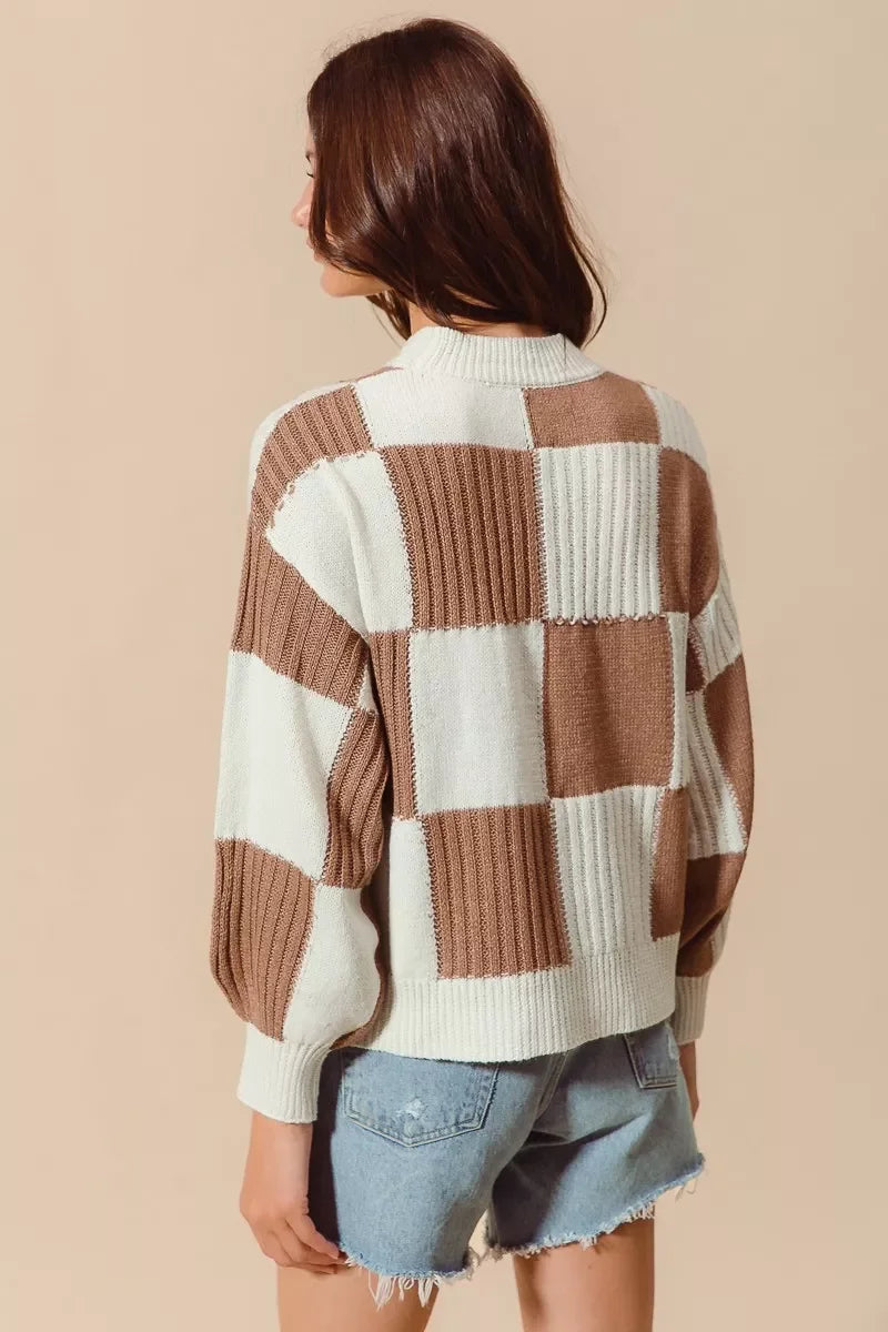 Brown and cream checkered knit sweater with ribbed texture, paired with denim shorts for a cozy, trendy look.