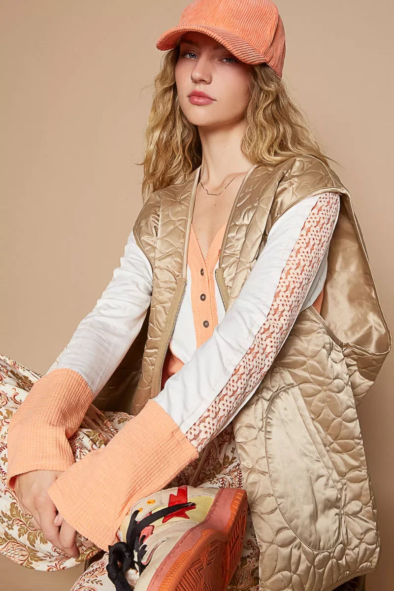 Woman in trendy quilted vest, orange cap, and patterned pants — stylish, affordable boho look