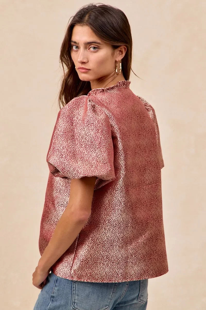 Woman wearing trendy pink patterned blouse with puff sleeves, styled with jeans for a happy, affordable look