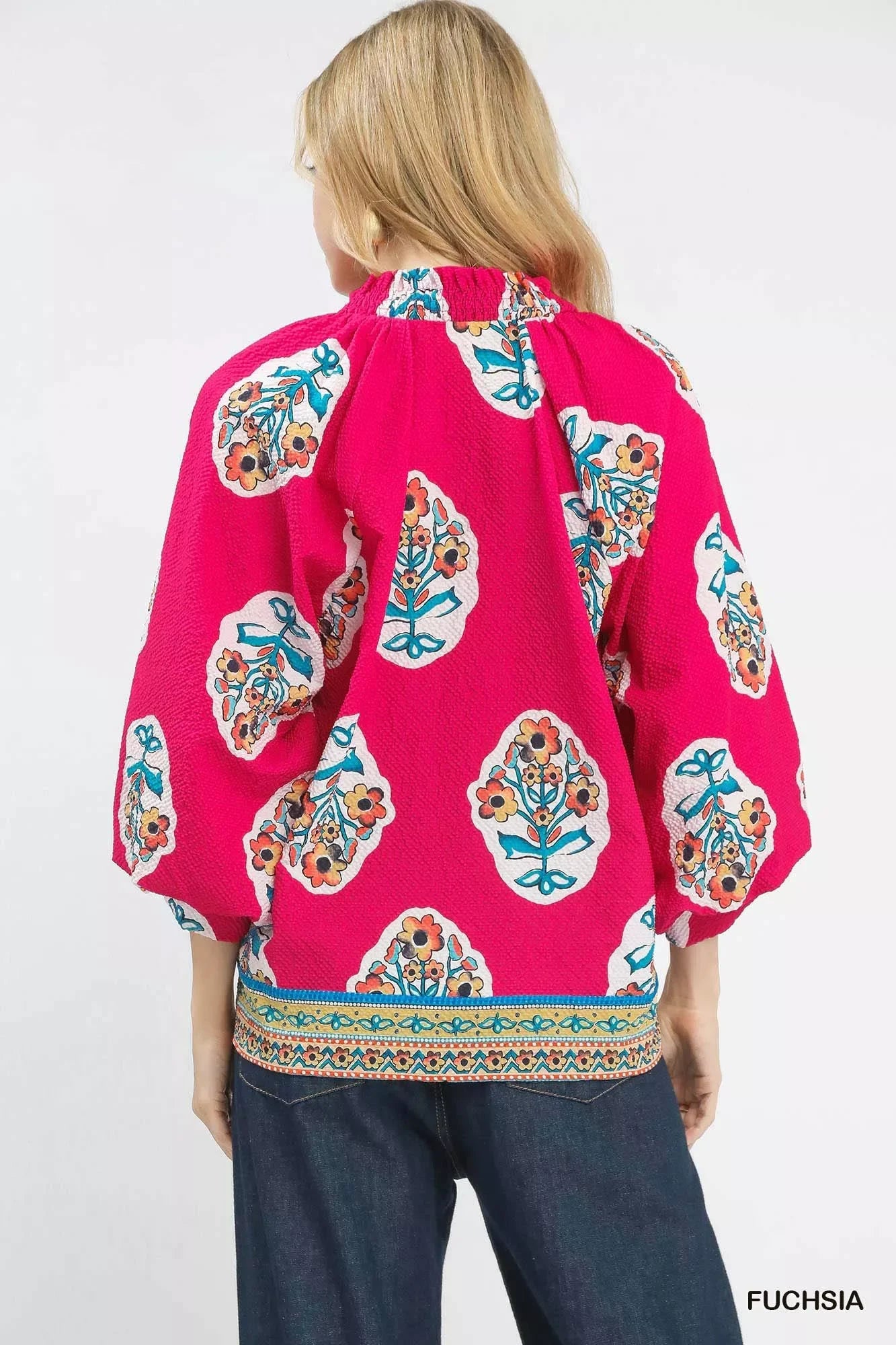 Fuchsia boho blouse with floral print, puff sleeves, and embroidered hem, styled with jeans